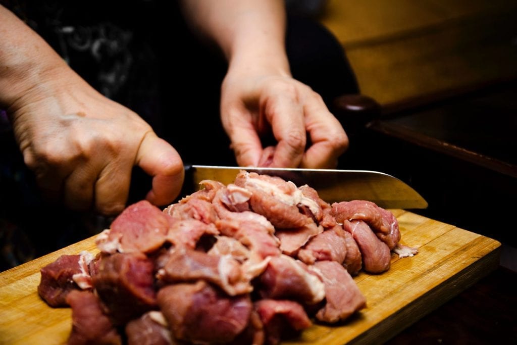slicing meat on a wooden chopping board