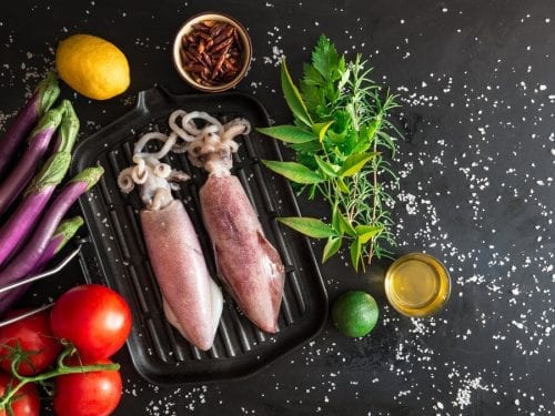 two raw squids with vegetables on the side