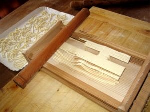Fresh spaghetti alla chitarra noodles being made on a chitarra
