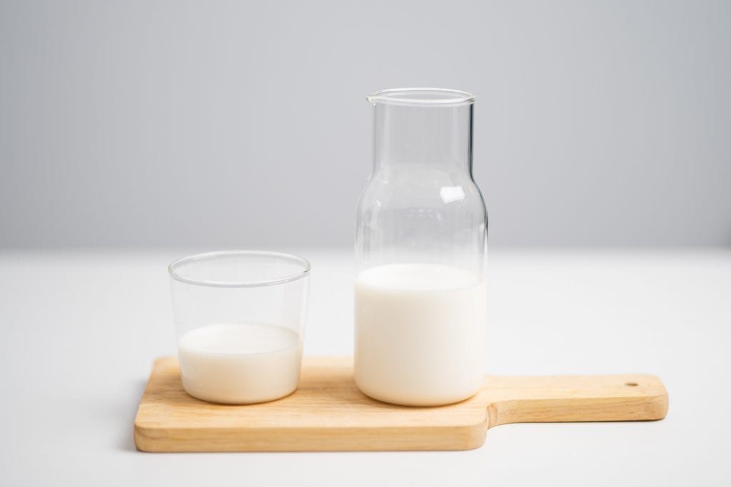 Pitcher and glass of milk on a wooden cutting board