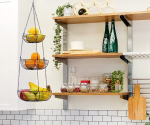 Various fruits in durable steel hanging fruit bowl near kitchen shelves