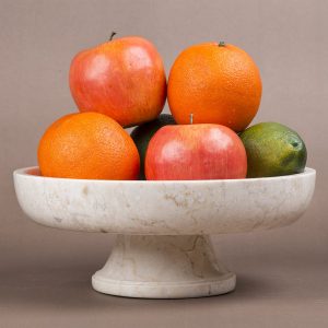 Assorted fruits on marble pedestal fruit bowl