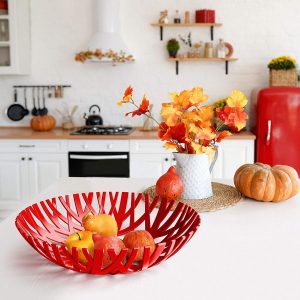 Various fruits on decorative red plastic fruit bowl on countertop