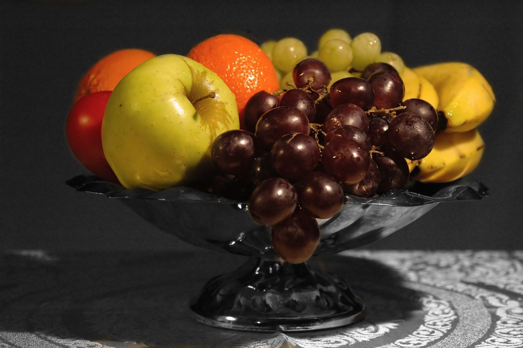 Fruits in pedestal silver fruit bowl on table