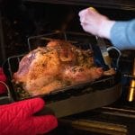 Two people preparing roast turkey with a tube turkey baster