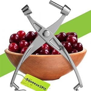Cherry Pitter Olive and Cherry Pitting Tool, with a bowl of cherries in a wooden bowl