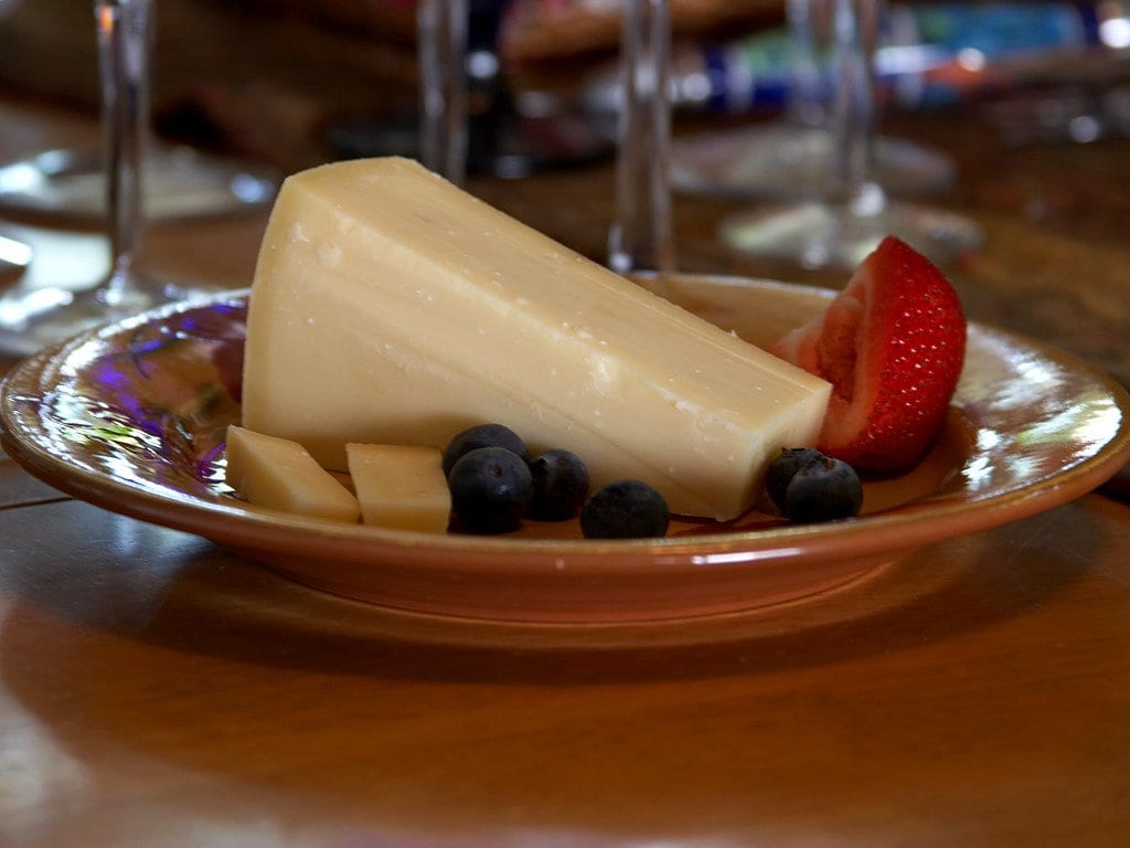 Gruyere cheese with blueberries and a slice of strawberry on a plate