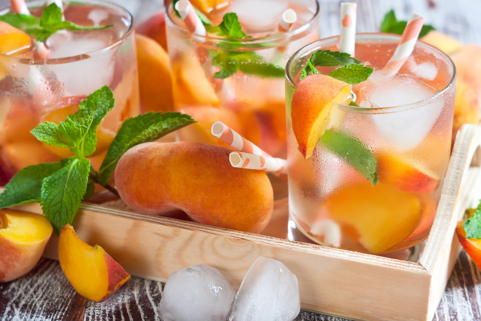 Glasses of Peach Mango Drink in a tray full of peaches