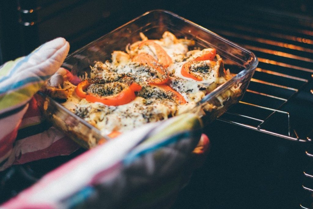 Person taking out dish from an oven using the best oven mitts