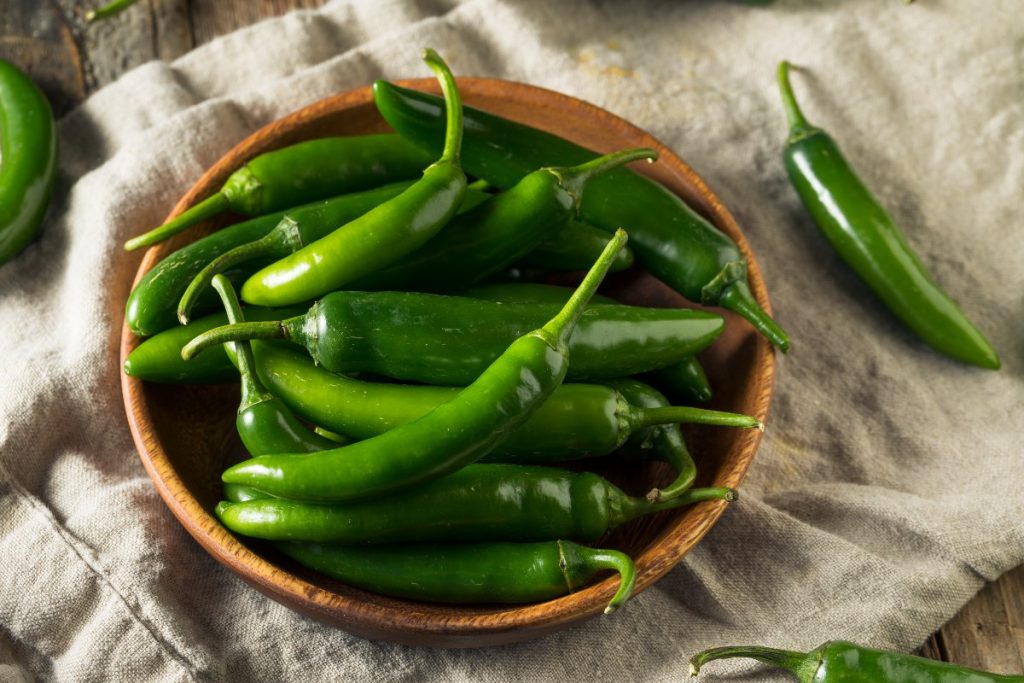 Pieces of green serrano pepper on a wooden bowl