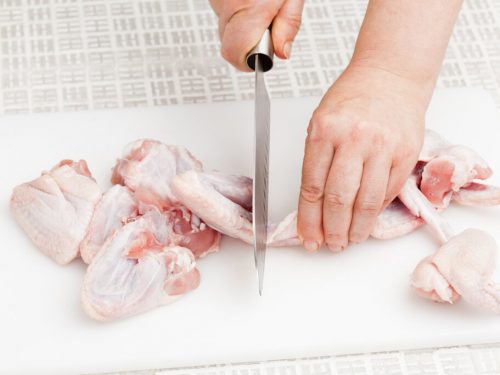 cutting raw chicken wings on a cutting board