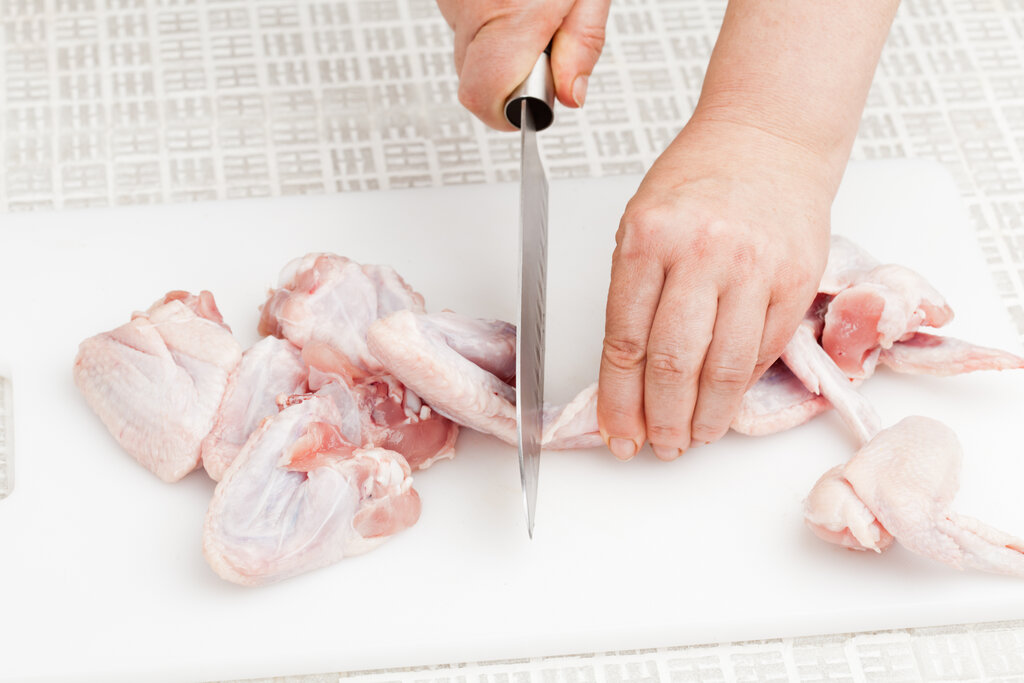 cutting raw chicken wings on a cutting board