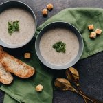 two bowls of green soup with bread