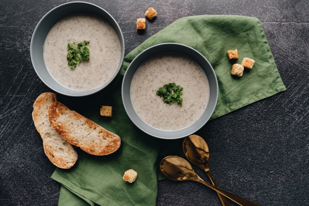 two bowls of green soup with bread