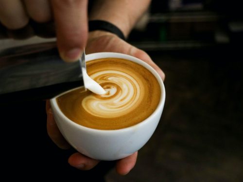 Person making latte, one of the many types of coffee drinks