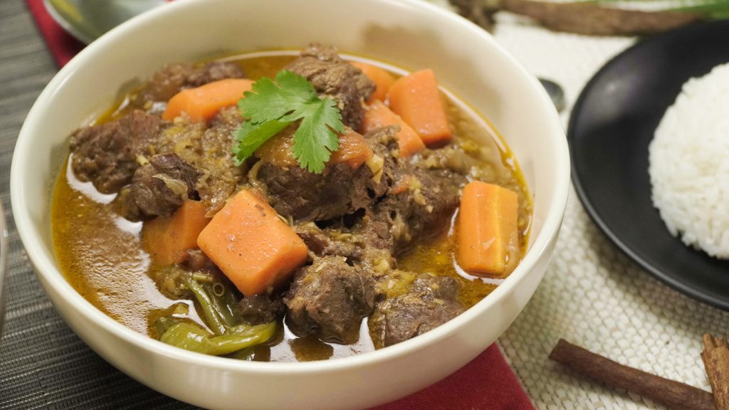 beef chunks, carrots, and cilantro leaves in a white bowl