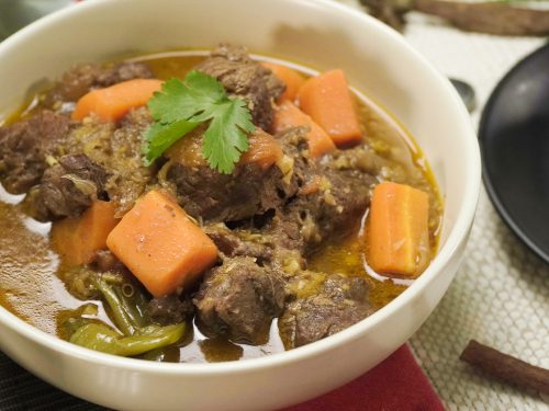 beef chunks, carrots, and cilantro leaves in a white bowl