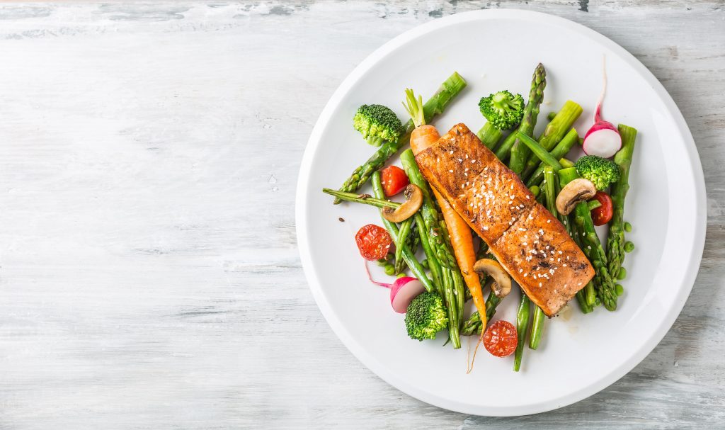 Roasted salmon steak with asparagos broccoli carrot tomatoes radish green beans and peas. Fish meal with fresh vegetable