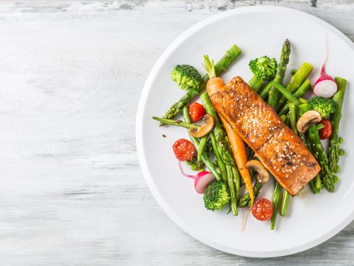 Roasted salmon steak with asparagos broccoli carrot tomatoes radish green beans and peas. Fish meal with fresh vegetable