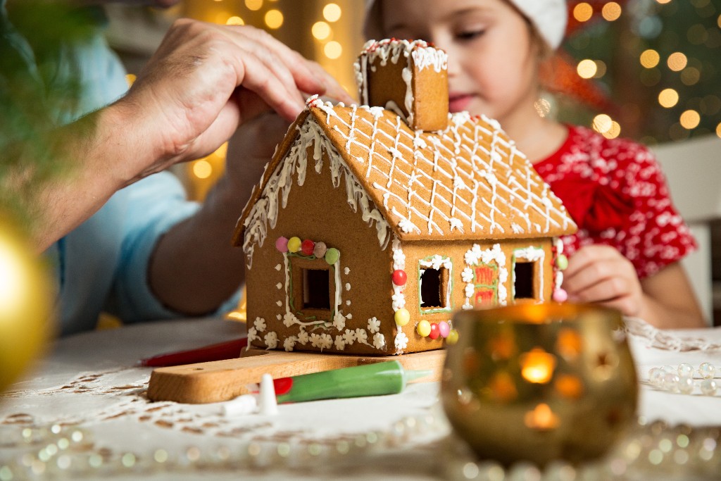 Man and child decorating a gingerbread house kit
