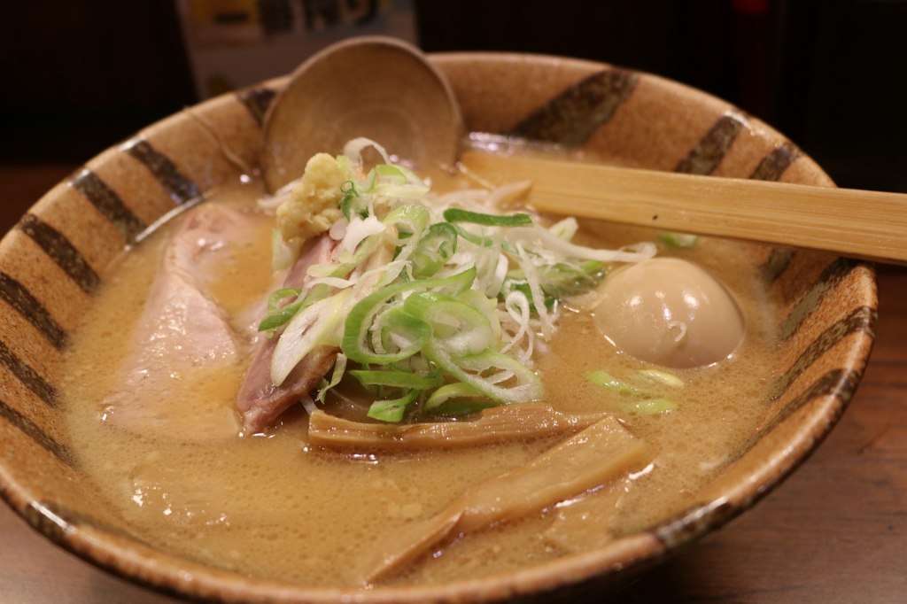 Bowl of miso ramen, topped with julienned scallions, boiled egg, fermented bamboo shoots, and chashu