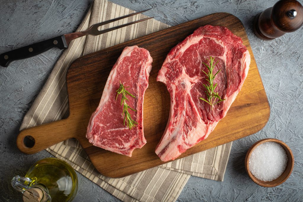 Raw piece of New York strip vs ribeye on a wooden board