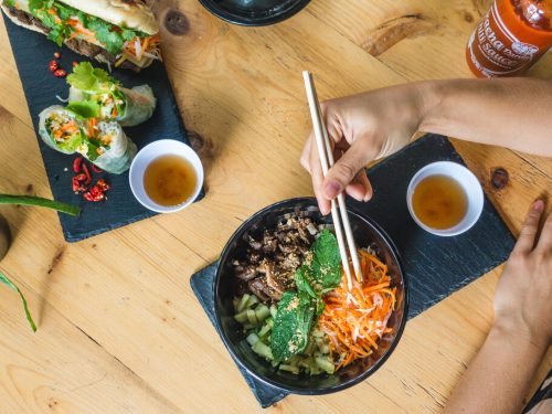 Vietnamese recipes such as spring rolls and pork noodle salad with chopsticks and hands