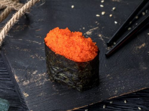 Piece of gunkan maki topped with masago or capelin roe