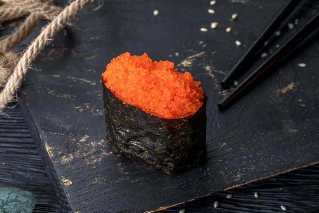 Piece of gunkan maki topped with masago or capelin roe