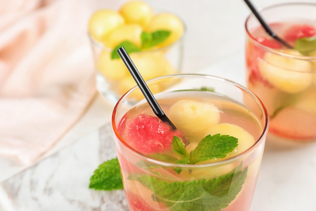 Glass with tasty watermelon and melon ball drink on table, closeup