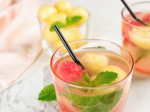 Glass with tasty watermelon and melon ball drink on table, closeup