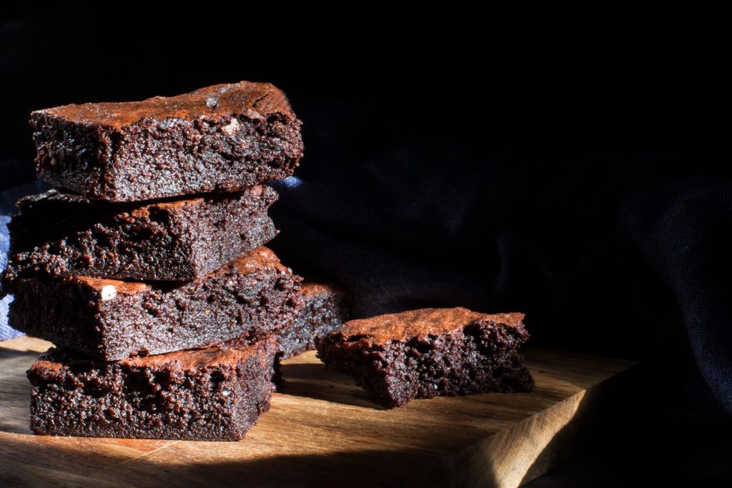 Chocolate brownie on the black background, side view, selective