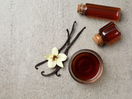 glass and bowls of vanilla extract on a gray background