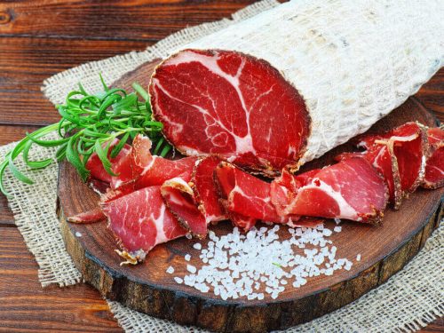 sliced capicola or coppa on a wooden chopping board