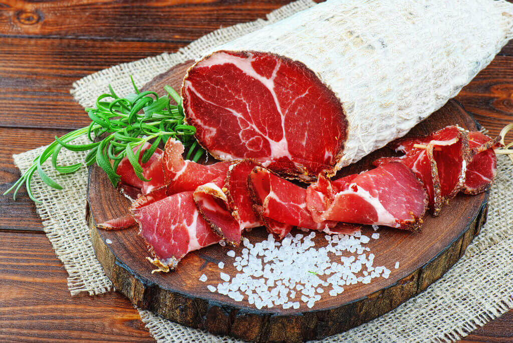sliced capicola or coppa on a wooden chopping board