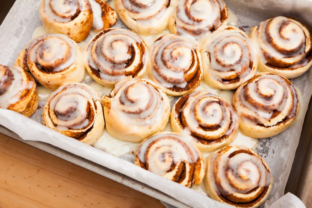 freshly baked homemade bisquick cinnamon rolls with milk sugar icing in baking dish