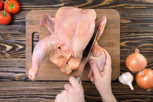 Person demonstrating how to cut up a whole chicken