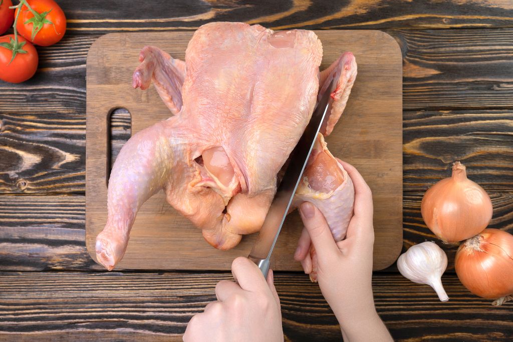 Person demonstrating how to cut up a whole chicken 