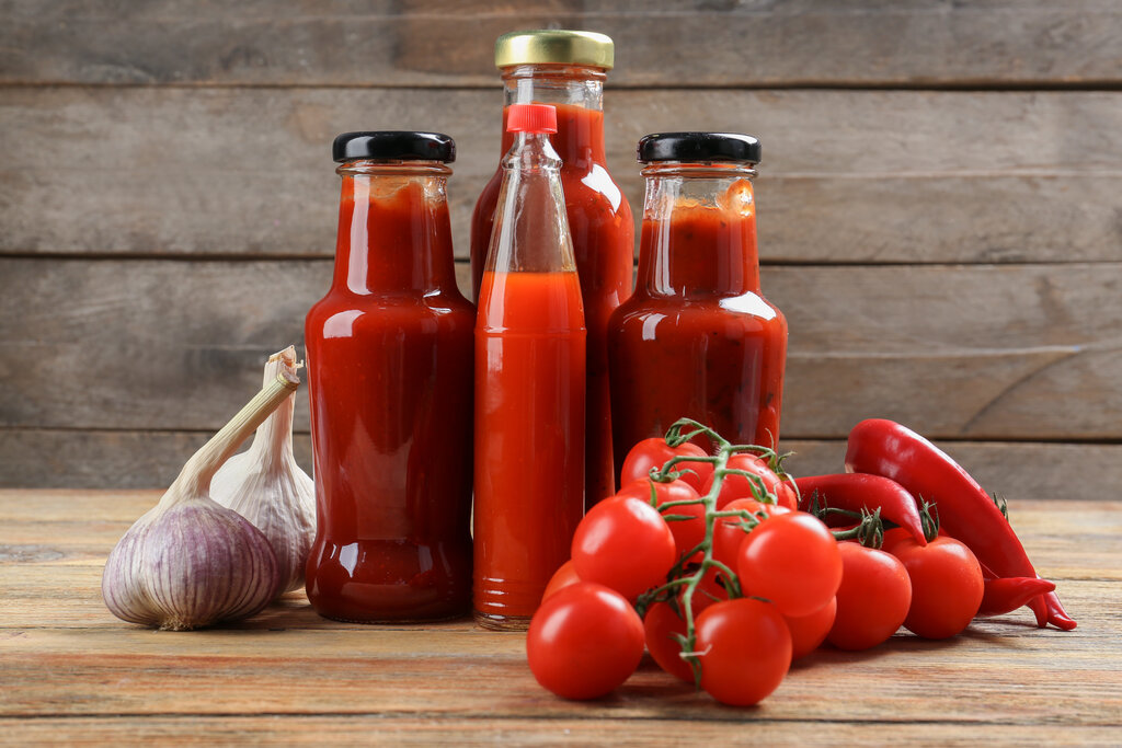 bottles with tasty tomato sauces and on wooden table, substitute for tomato sauce