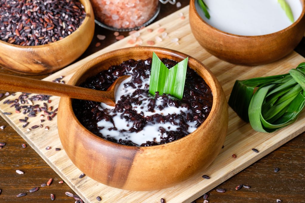 Black rice pudding with coconut milk in a wooden bowl