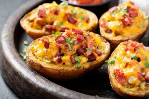 four baked potatoes in a dish