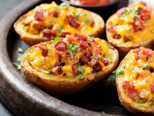 four baked potatoes in a dish