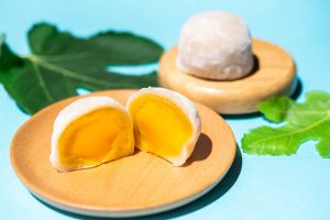 mango mochi sliced in half on a wooden plate