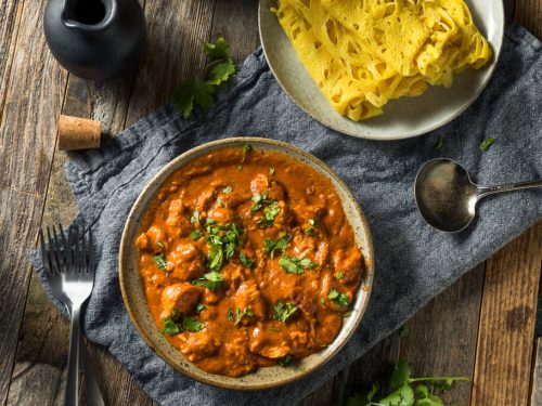 plate of butter chicken on wooden table