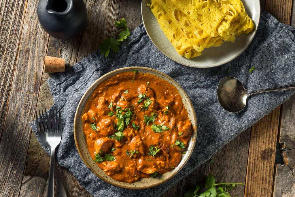 plate of butter chicken on wooden table