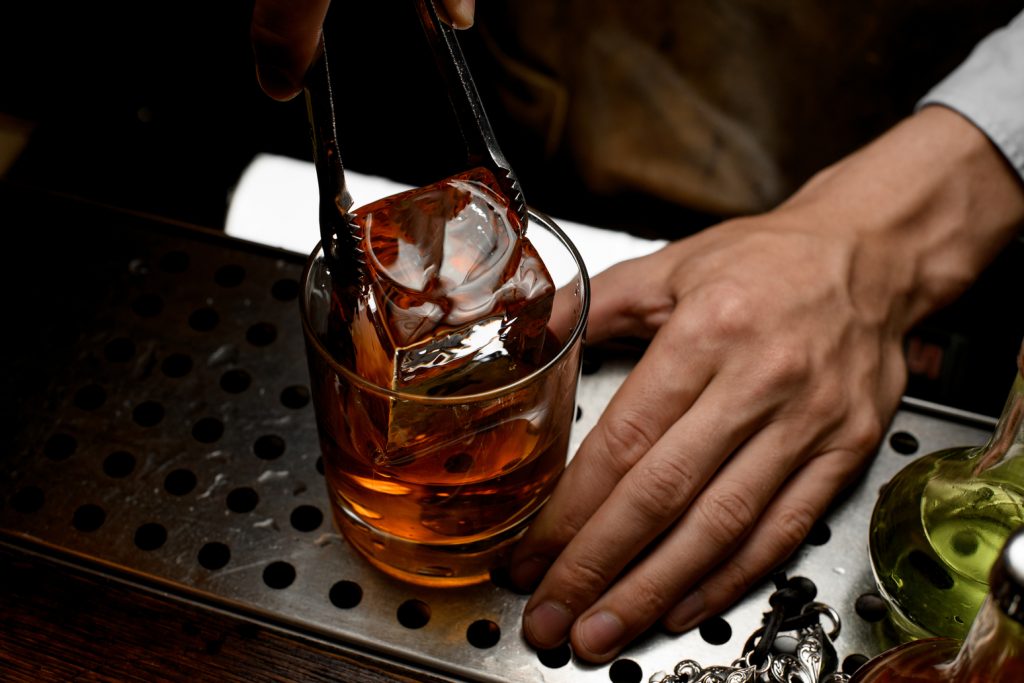Bartender cutting clear ice cube using a knife