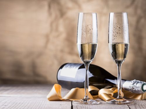 half full champagne glasses with a champagne bottle laying in the back, brut vs dry