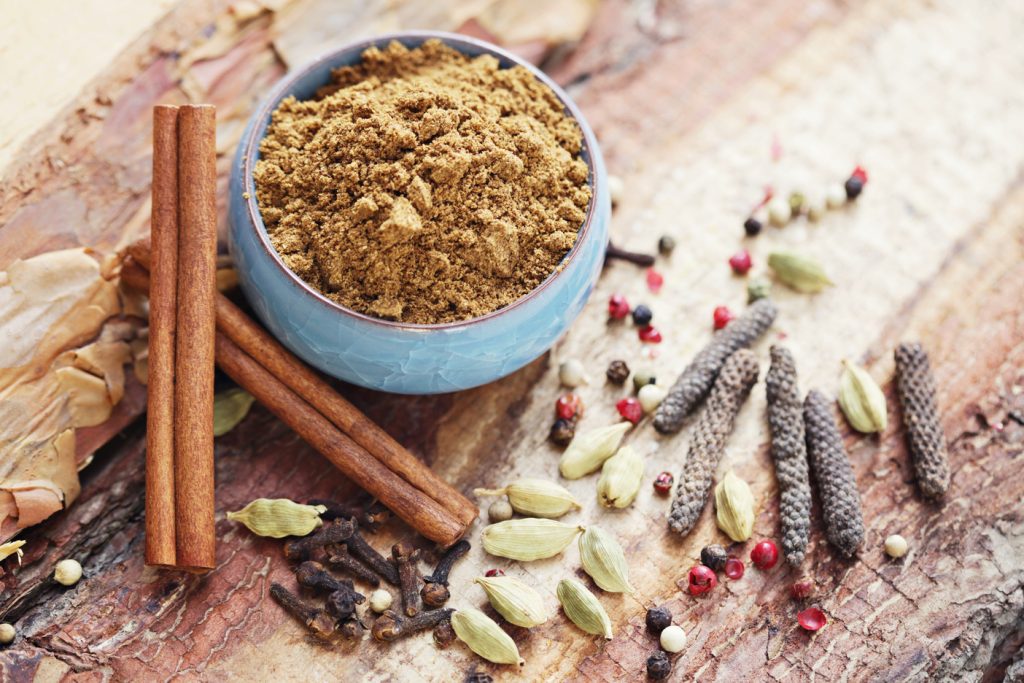 garam masala in a bowl surrounded by cinnamon sticks, peppercorns, and other spices, garam masala substitute