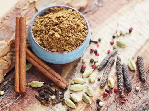 garam masala in a bowl surrounded by cinnamon sticks, peppercorns, and other spices, garam masala substitute