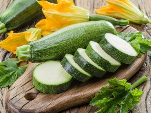 zucchini and zucchini slices on wooden chopping board